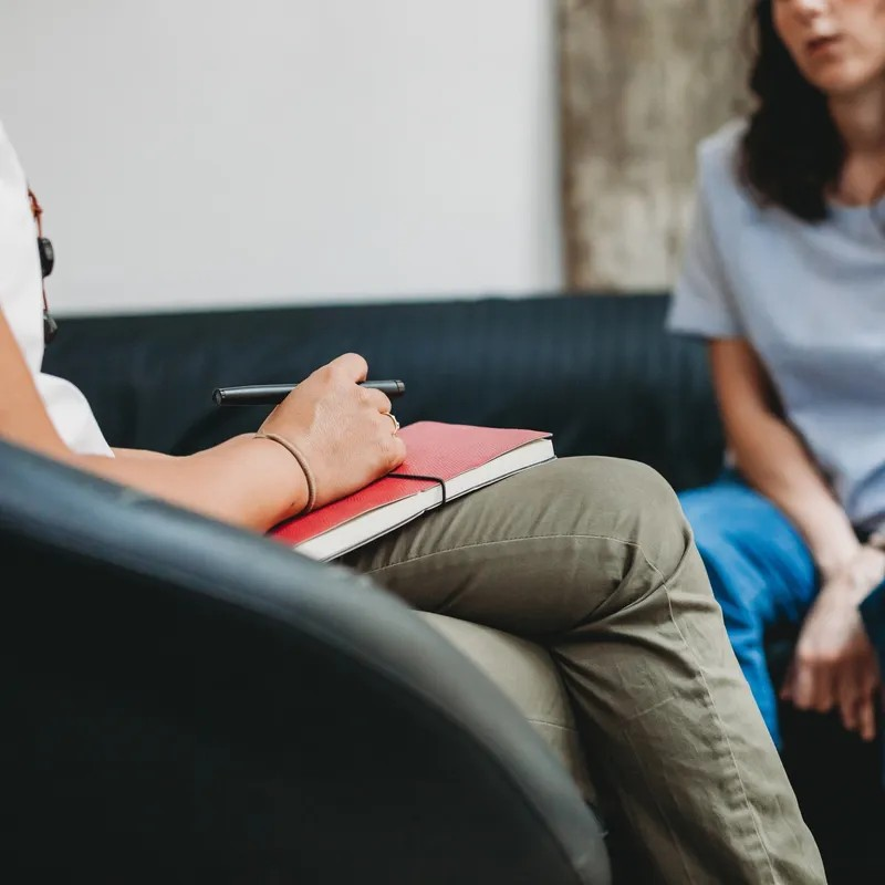 Therapist taking notes during one-on-one counseling session, representing personalized mental health and addiction treatment at Rooted Stillness in Newport Beach