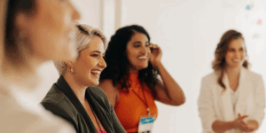 Group of women smiling and engaging in therapy session, representing supportive community and mental health treatment at Rooted Stillness in Newport Beach