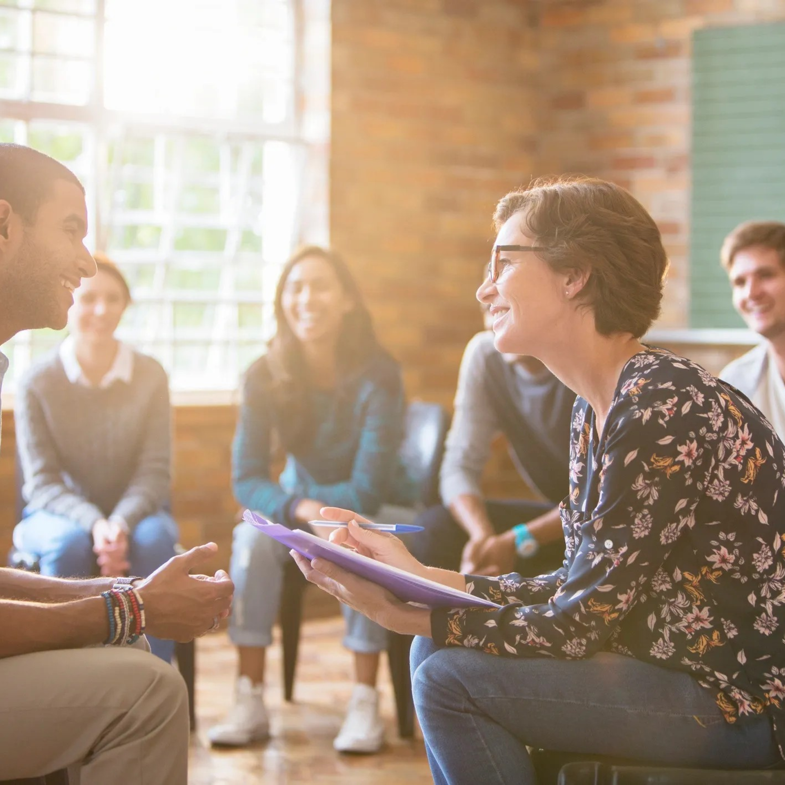 Therapist leading group counseling session with clients, representing supportive mental health and addiction treatment at Rooted Stillness in Newport Beach